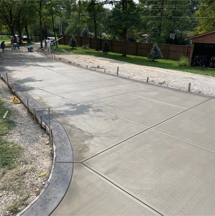 Concrete driveway installation by Barton Pool Company - freshly poured residential driveway with curved decorative border and expansion joints