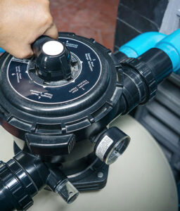 Close-up of a pool filtration system valve being adjusted for maintenance