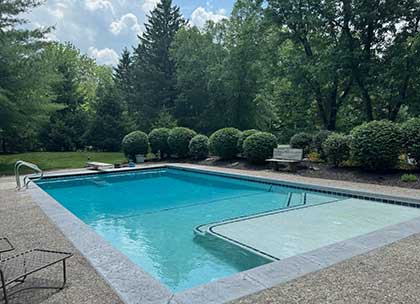 Completed inground pool with tanning ledge and surrounding landscaping