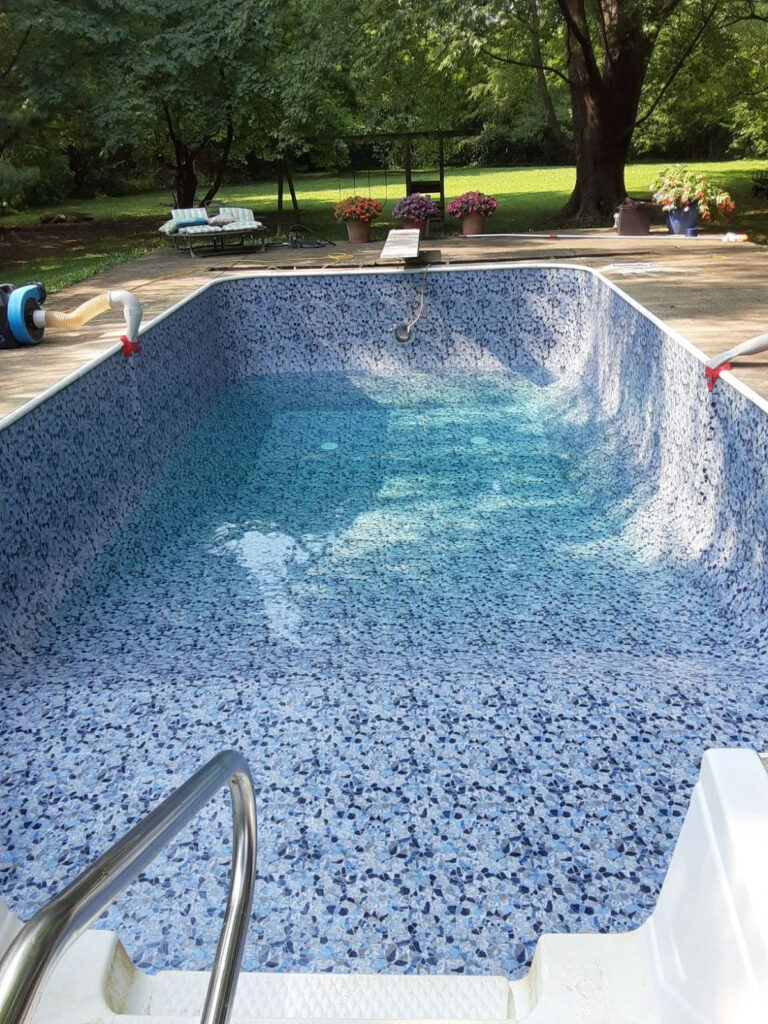 Vinyl liner replacement after photo - renovated inground pool with new blue mosaic pattern vinyl liner and fresh clean water by Barton Pool Company