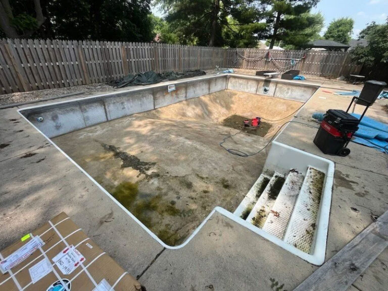 Vinyl liner replacement before photo - empty L-shaped inground pool with old deteriorated liner and algae staining by Barton Pool Company