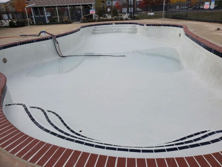 Pool renovation after photo - restored inground pool with fresh white surface, new tile border, and brick coping by Barton Pool Company