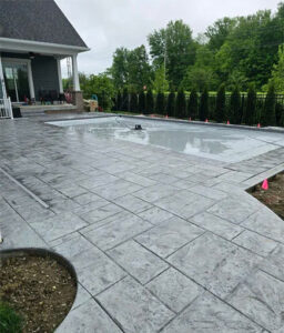 Concrete service by Barton Pool Company - stamped concrete pool deck installation with gray stone pattern finish