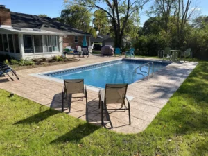 Vinyl liner pool with stamped concrete deck and patio seating in a suburban backyard