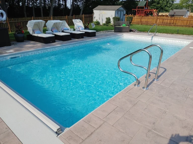 Vinyl liner pool with light blue finish, stamped concrete patio, and poolside loungers