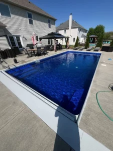 Rectangular vinyl liner pool with deep blue liner and surrounding concrete patio