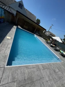 Rectangular vinyl liner pool with wide entry steps and stamped concrete patio