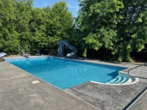 Vinyl liner pool with curved entry steps, stamped concrete deck, and backyard slide