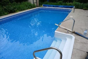 Rectangular vinyl liner pool with molded white entry steps and concrete deck