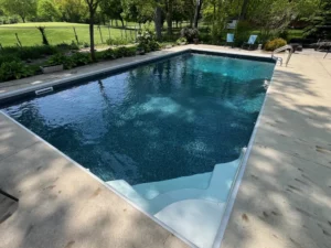 Rectangular vinyl liner pool with corner entry steps and surrounding concrete patio