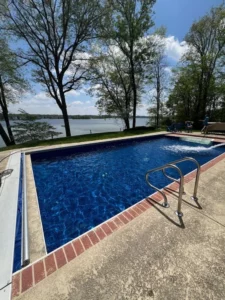 Rectangular vinyl liner pool with brick coping and a lake view