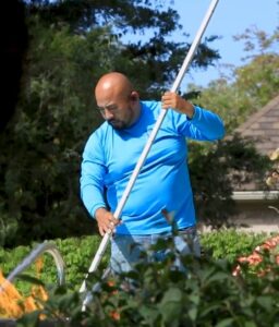 Barton Pool Company technician brushing a residential pool during weekly maintenance